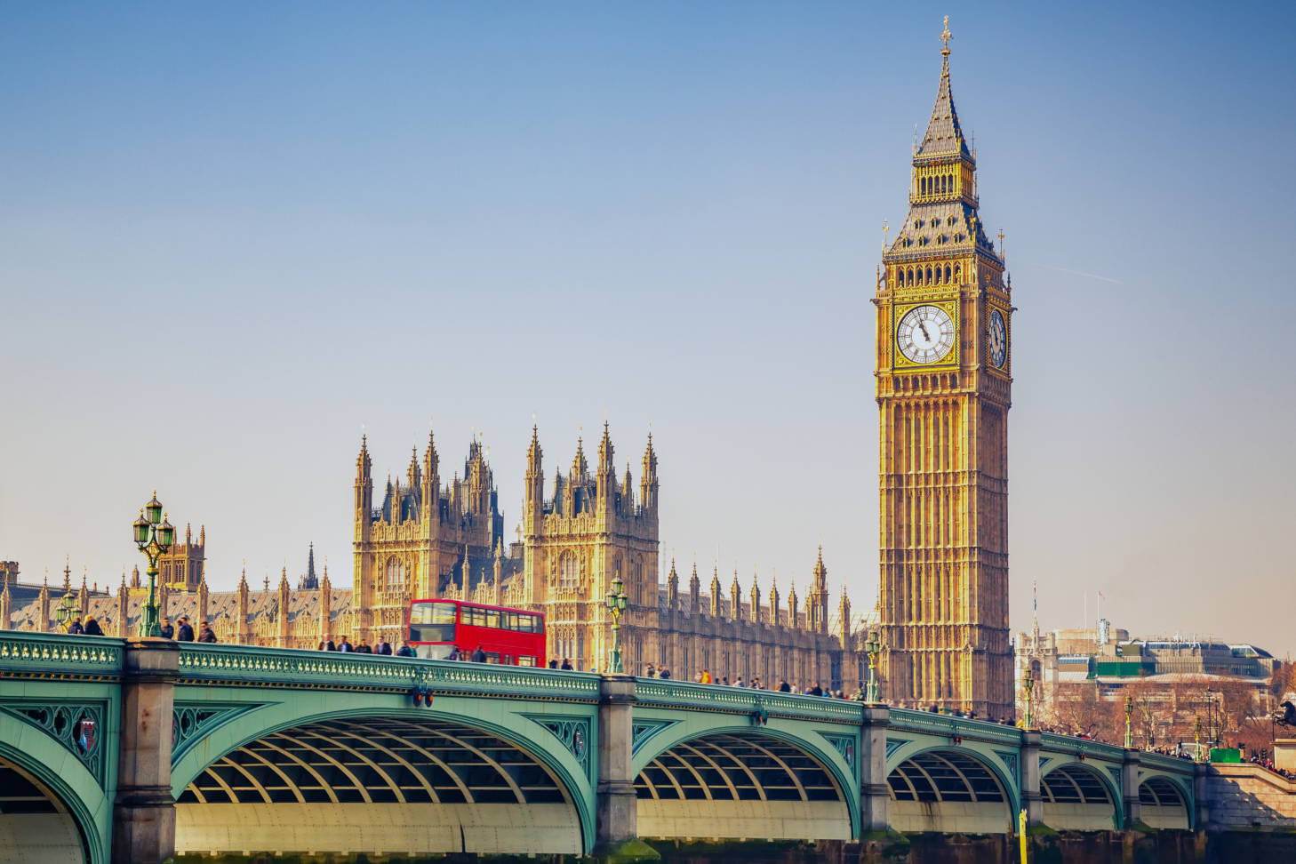 Red double-decker bus crossing Westminster Bridge, with Big Ben in the background