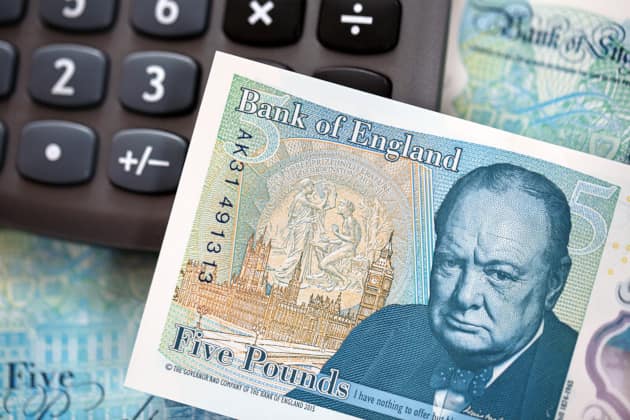 Close-up of British pound banknotes next to a pocket calculator