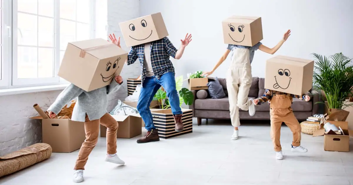 Happy family dancing with cardboard boxes on their heads in a cozy living room