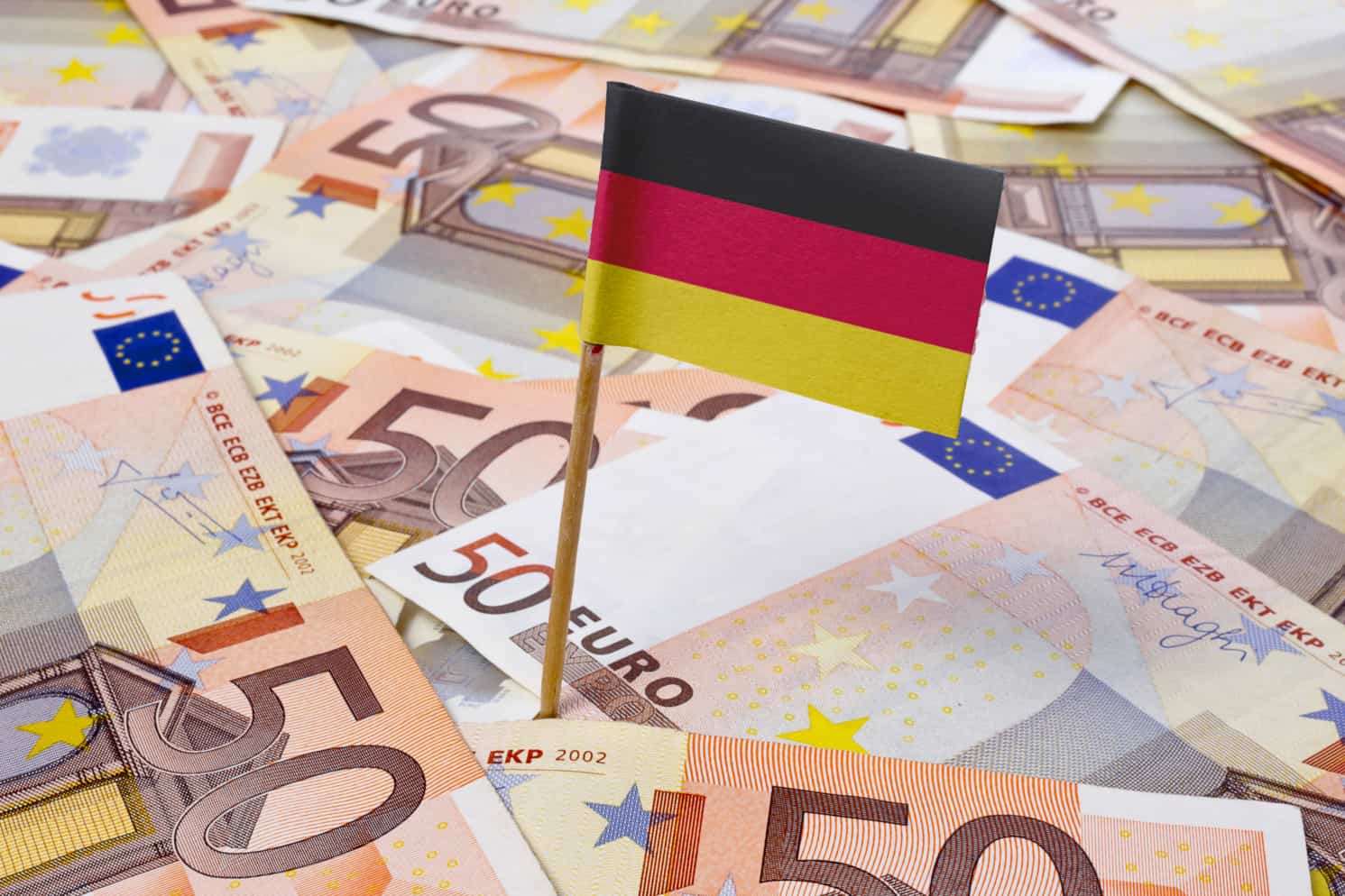 Miniature flag of Germany on top of a pile of Euro banknotes