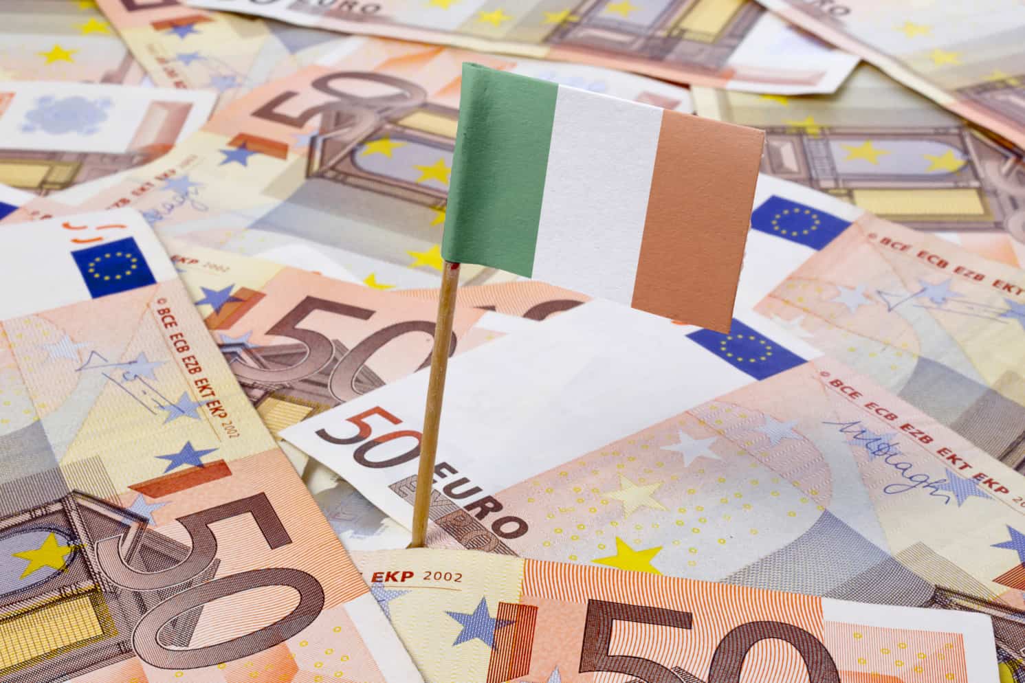 Miniature flag of Ireland on top of a pile of Euro banknotes