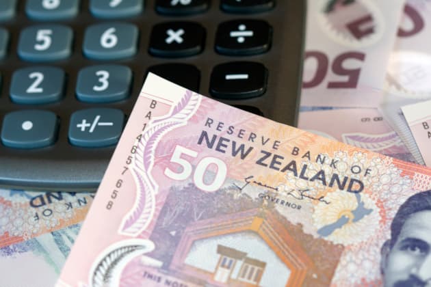 Close-up of New Zealand dollar (NZD) banknotes next to a pocket calculator