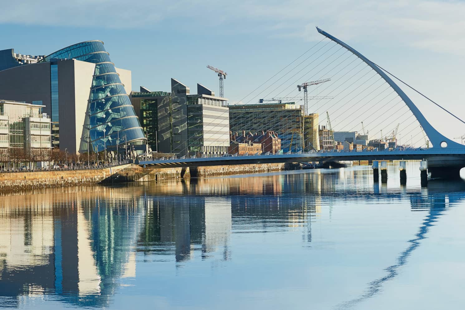 Office buildings along the north shore of the River Liffey with the iconic Samuel Beckett Bridge in the foreground
