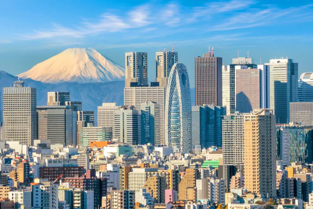 Skyline of the Shinjuku ward in Tokyo, with its crowded skyscrapers soaring against the horizon dominated by the majestic Mount Fuji